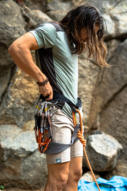 Introducing the Men's 10" Rocky Mountain Board Shorts by Belong Designs: a pair of gray knee-length shorts crafted from Venterrex material for quick dry technology. These shorts feature a subtle texture, a black drawstring on the waistband, side pockets, and a small black logo tag with white "MB" letters on the front left hem.