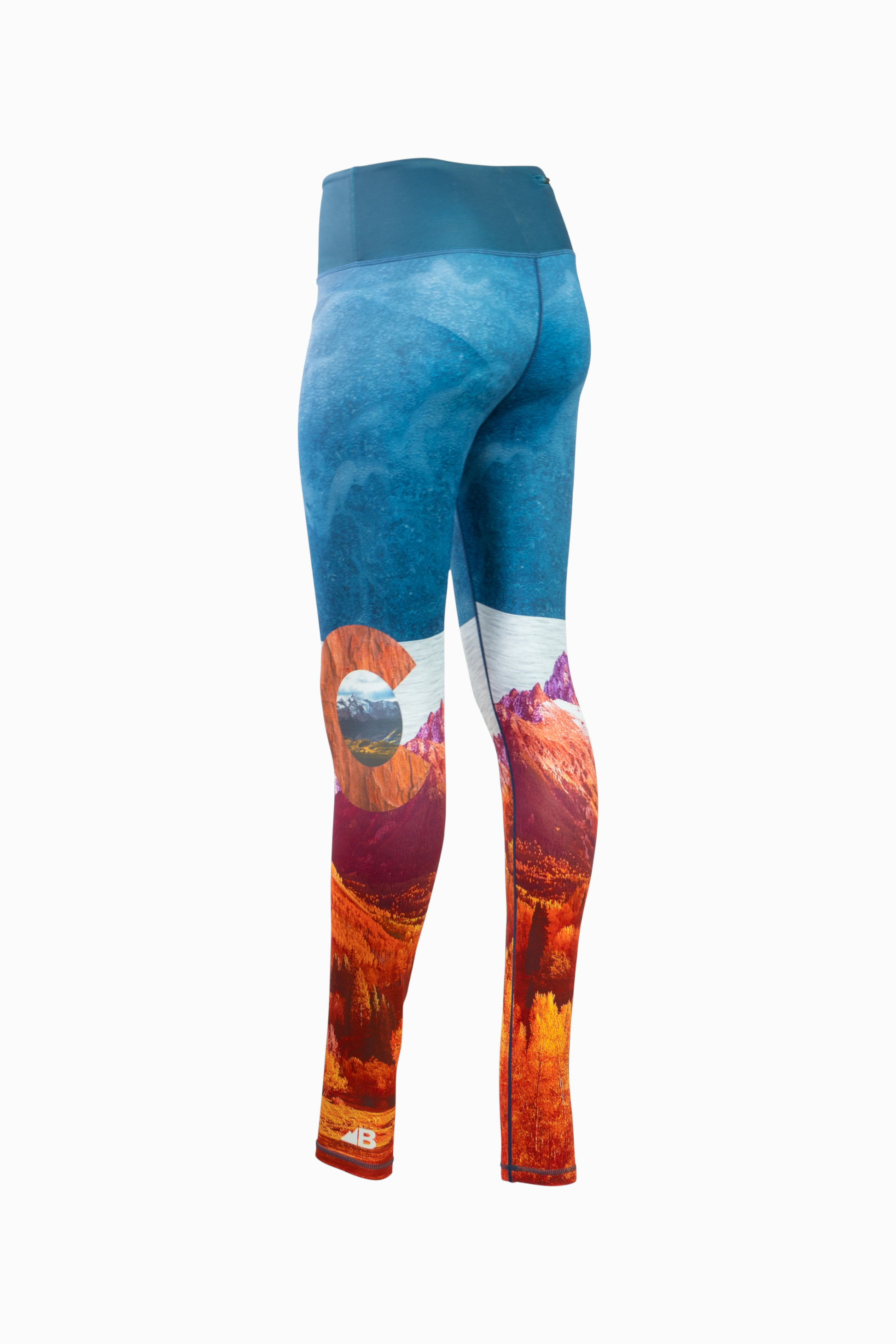 A pair of women's Wayfarer Leggings from Belong Designs featuring a vivid landscape design. The bottom half showcases rocky mountains in red and orange hues, transitioning to blue and white at the top, resembling a sky. Made from breathable PrimaFlex material, the leggings have a fitted style and a solid teal waistband.