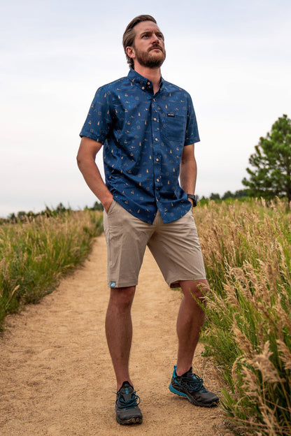 Introducing the Men's 10" Rocky Mountain Board Shorts by Belong Designs: a pair of gray knee-length shorts crafted from Venterrex material for quick dry technology. These shorts feature a subtle texture, a black drawstring on the waistband, side pockets, and a small black logo tag with white "MB" letters on the front left hem.