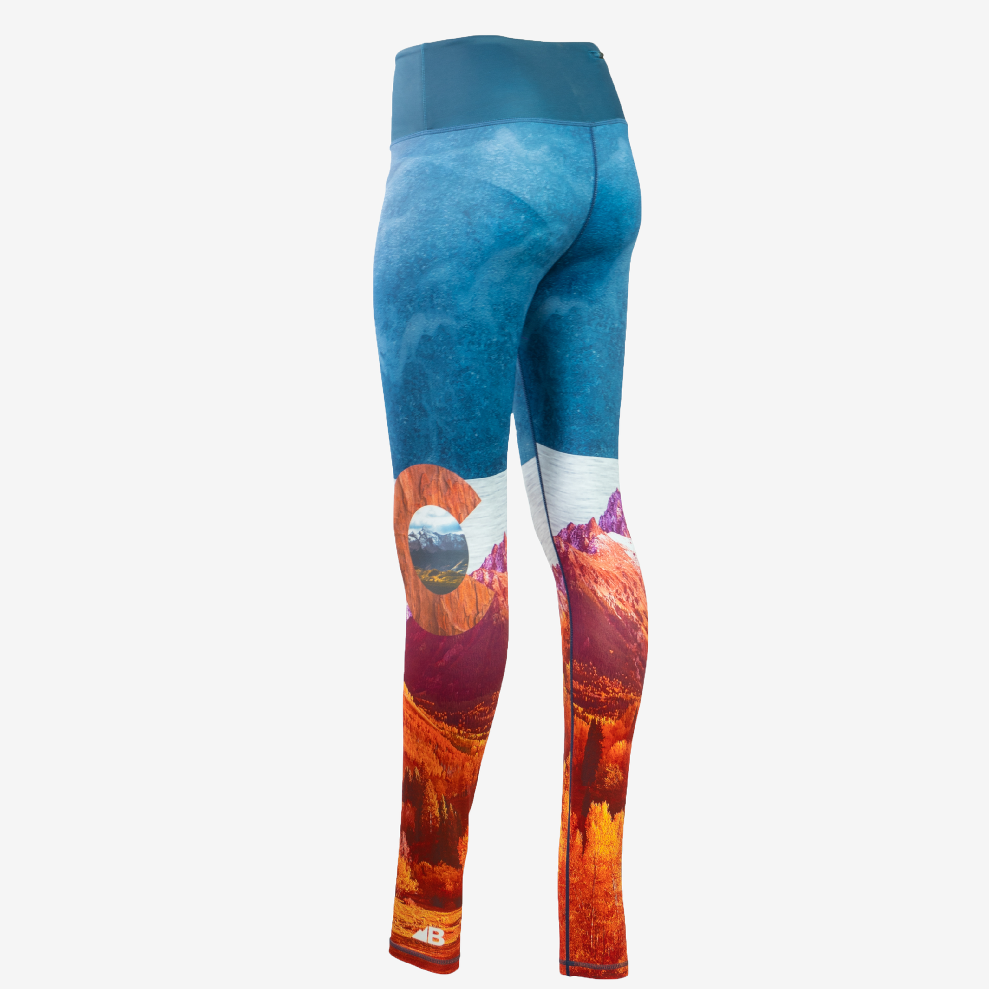 A pair of women's Wayfarer Leggings from Belong Designs featuring a vivid landscape design. The bottom half showcases rocky mountains in red and orange hues, transitioning to blue and white at the top, resembling a sky. Made from breathable PrimaFlex material, the leggings have a fitted style and a solid teal waistband.